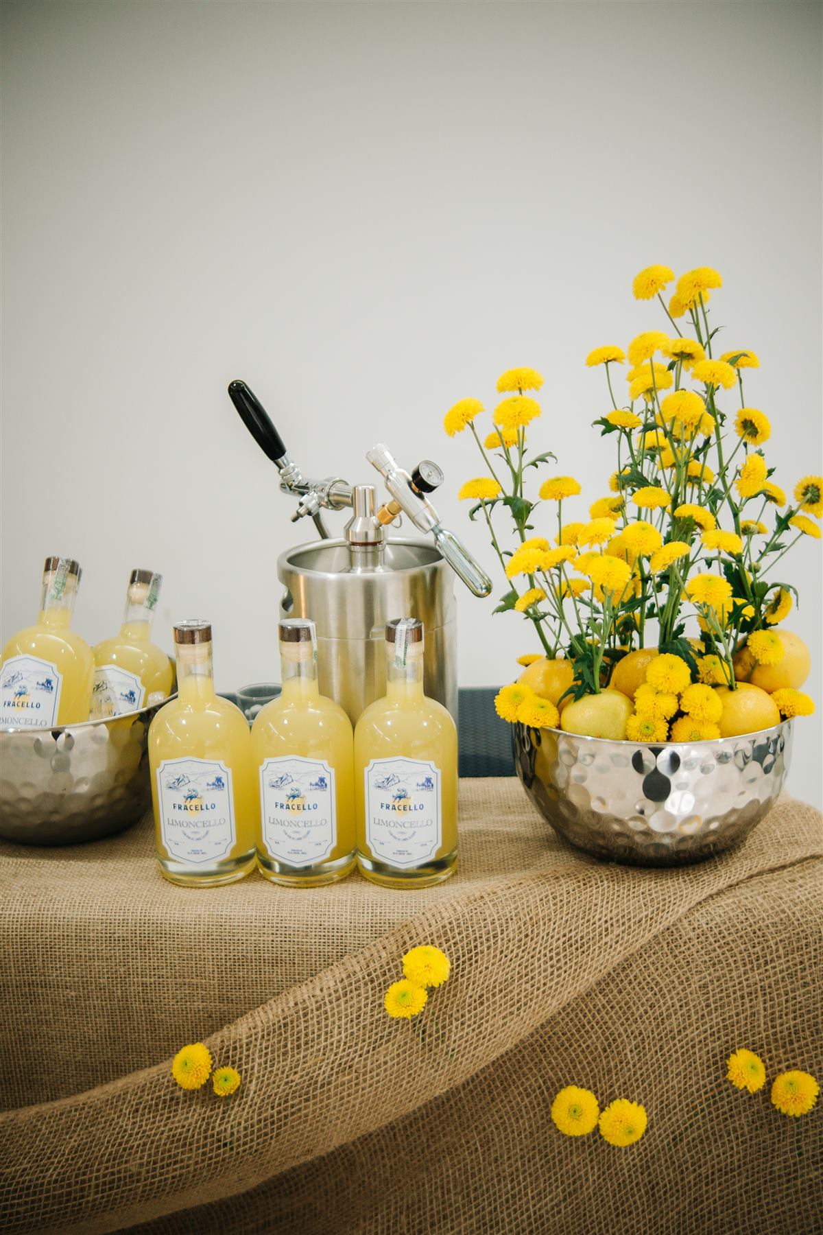 Mesa de evento com garrafas Fracello e flores amarelas